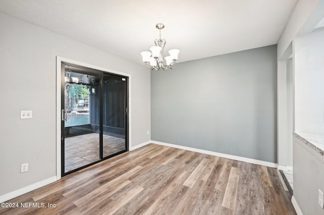 unfurnished room featuring hardwood / wood-style flooring and an inviting chandelier