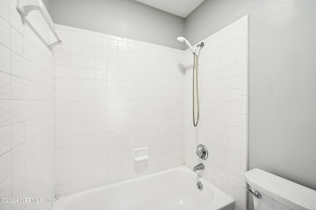 bathroom with toilet and tiled shower / bath