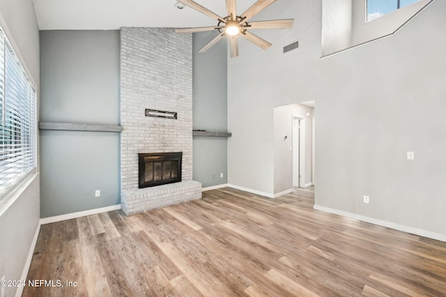 unfurnished living room with a fireplace, ceiling fan, light hardwood / wood-style flooring, and high vaulted ceiling