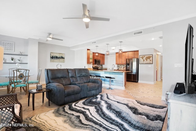 tiled living room featuring ceiling fan, crown molding, and sink