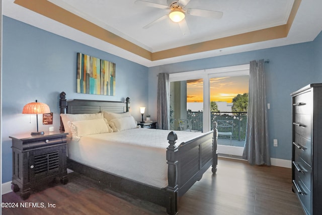 bedroom featuring ornamental molding, a tray ceiling, ceiling fan, and dark wood-type flooring