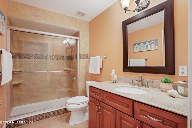 bathroom with tile patterned floors, vanity, toilet, and a shower with door