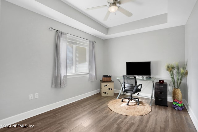 office space featuring a tray ceiling, ceiling fan, and dark hardwood / wood-style floors