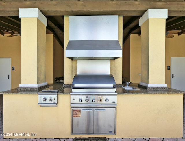 kitchen with beam ceiling, sink, and wall chimney range hood