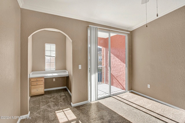 doorway to outside with dark carpet, built in desk, and ornamental molding