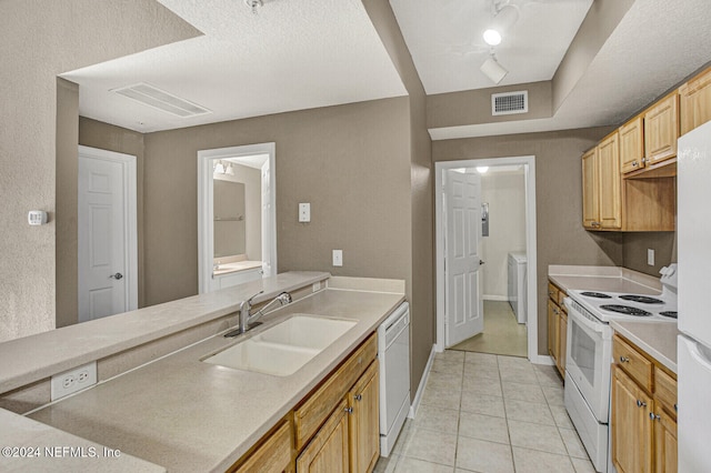 kitchen featuring white appliances, sink, light tile patterned floors, a textured ceiling, and separate washer and dryer