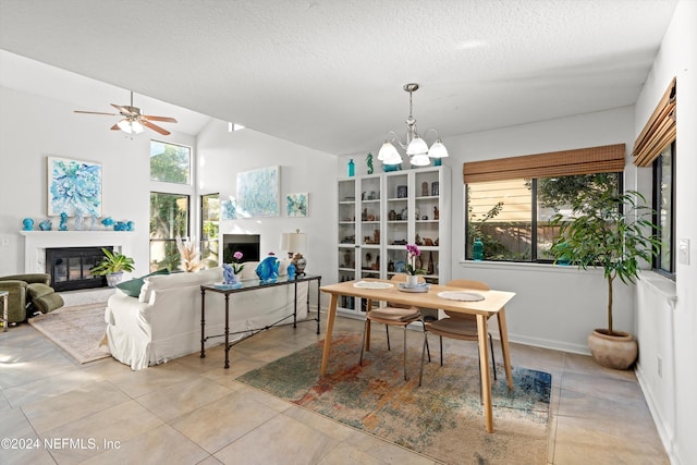 tiled dining area featuring ceiling fan with notable chandelier, a textured ceiling, and vaulted ceiling