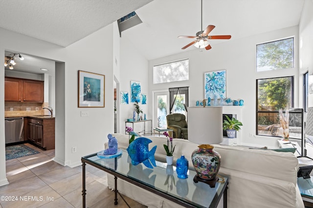 living room featuring a textured ceiling, ceiling fan, sink, light tile patterned floors, and high vaulted ceiling