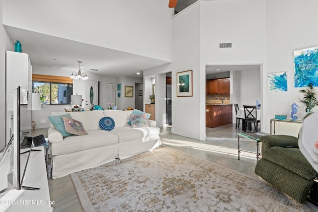 living room with sink, a high ceiling, and an inviting chandelier