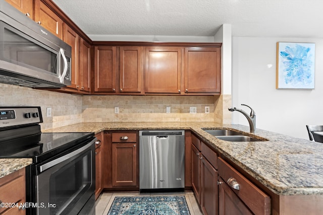 kitchen featuring light stone counters, sink, light tile patterned flooring, and appliances with stainless steel finishes