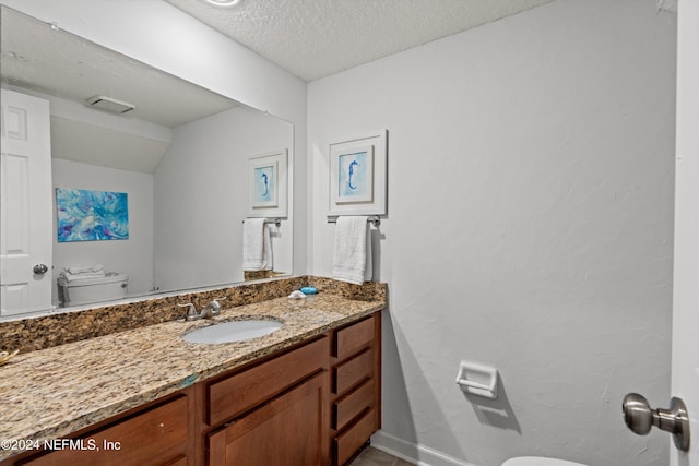 bathroom featuring vanity, a textured ceiling, and toilet