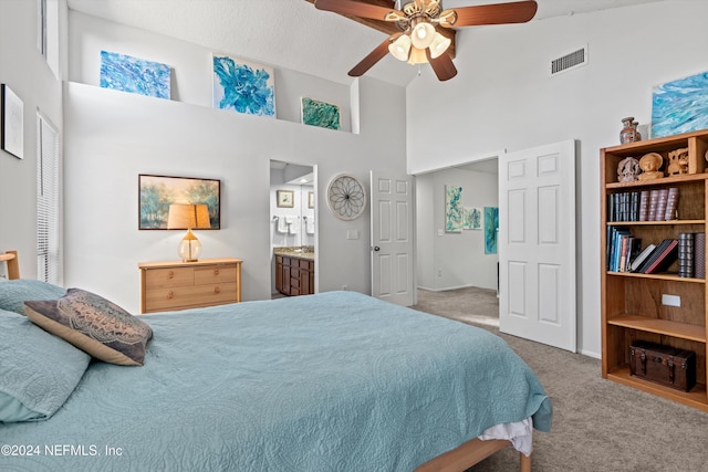 carpeted bedroom with connected bathroom, ceiling fan, and a towering ceiling