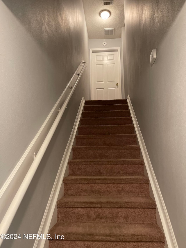 staircase with a textured ceiling