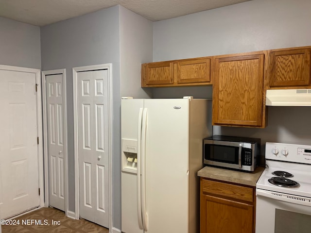 kitchen with dark parquet flooring, white appliances, and a textured ceiling