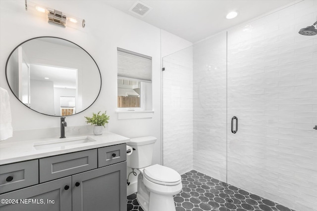 bathroom with tile patterned flooring, vanity, toilet, and a shower with shower door