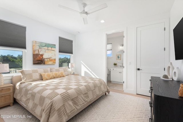 bedroom with ensuite bathroom, light hardwood / wood-style flooring, and ceiling fan