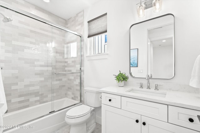 full bathroom with combined bath / shower with glass door, vanity, and toilet