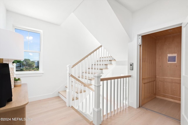 staircase featuring wood-type flooring and elevator