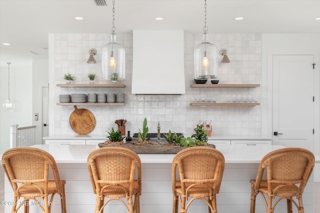 bar featuring decorative backsplash, white cabinets, and hanging light fixtures