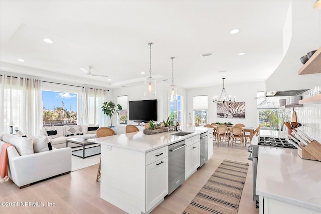 kitchen with light hardwood / wood-style flooring, an island with sink, decorative light fixtures, white cabinetry, and stainless steel appliances