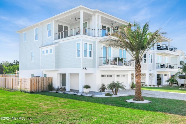 rear view of house with a lawn, ceiling fan, a garage, and a balcony