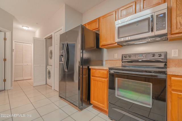 kitchen with stacked washer and dryer, light tile patterned floors, and stainless steel appliances