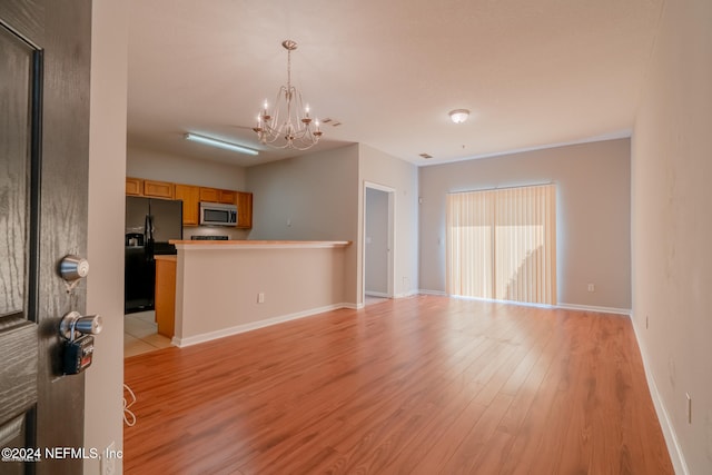 unfurnished living room with light wood-type flooring and an inviting chandelier