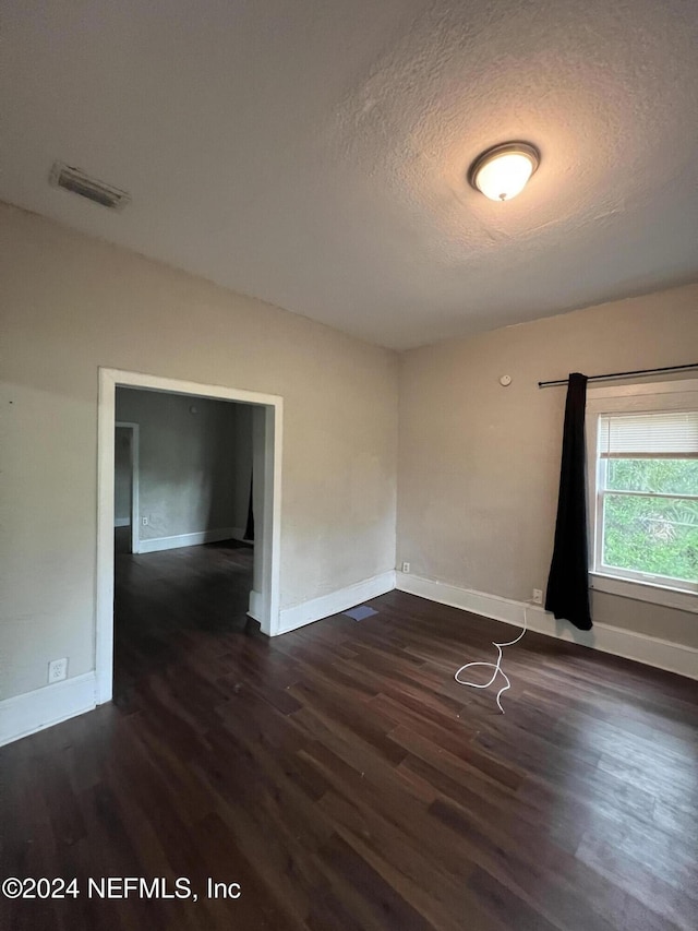 empty room featuring a textured ceiling and dark hardwood / wood-style floors