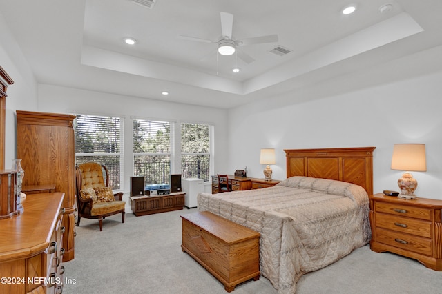 bedroom featuring light colored carpet, a raised ceiling, and ceiling fan