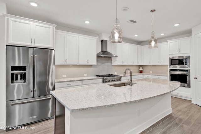 kitchen featuring white cabinetry, stainless steel appliances, wall chimney range hood, and light hardwood / wood-style floors