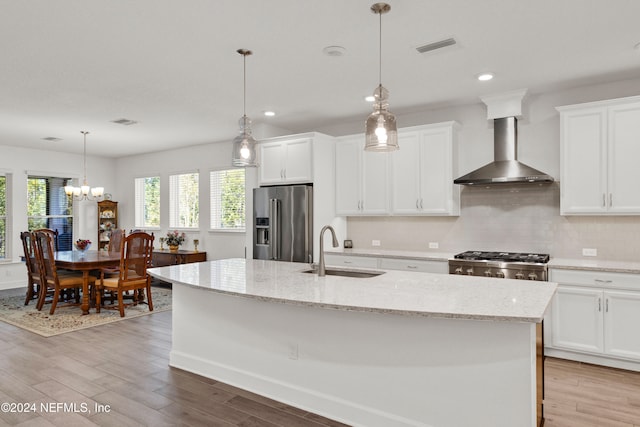 kitchen with wall chimney exhaust hood, sink, white cabinetry, and stainless steel appliances