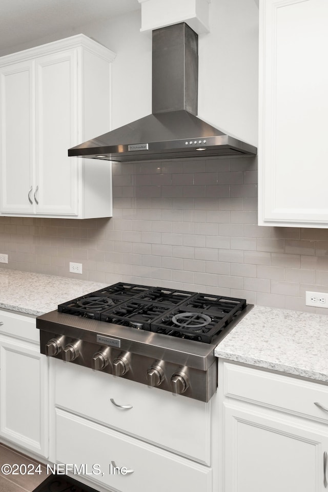 kitchen with white cabinets, decorative backsplash, wall chimney range hood, and stainless steel gas stovetop