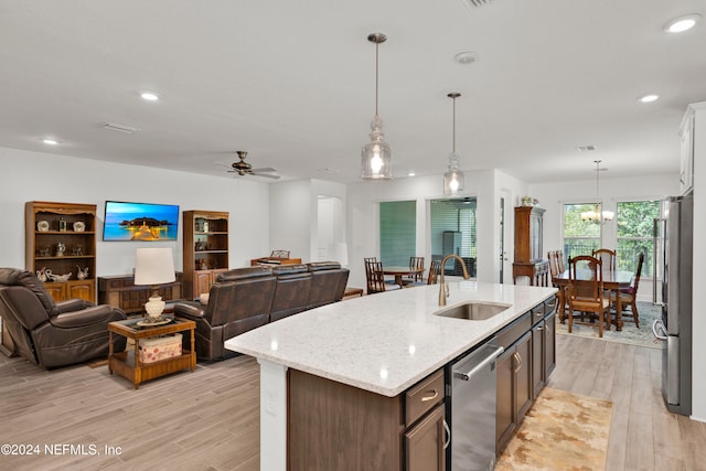 kitchen featuring appliances with stainless steel finishes, ceiling fan with notable chandelier, light hardwood / wood-style floors, and sink