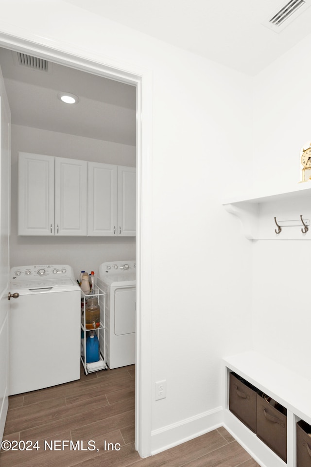 clothes washing area with washer and clothes dryer, dark hardwood / wood-style floors, and cabinets