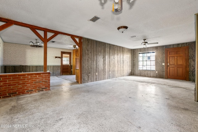 spare room featuring ceiling fan, a textured ceiling, and wooden walls