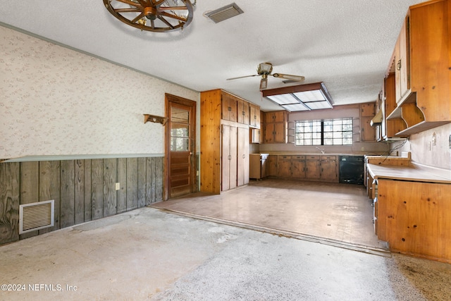 kitchen featuring ceiling fan, black dishwasher, a textured ceiling, and wooden walls