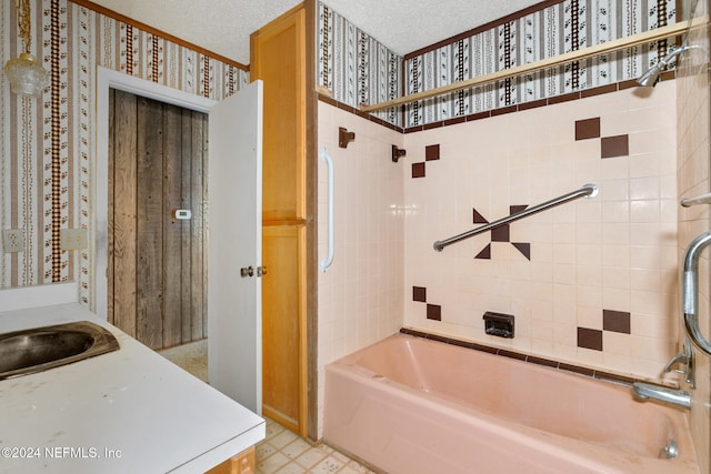 bathroom with sink, a textured ceiling, and tiled shower / bath