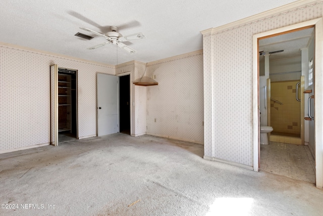 unfurnished bedroom with ensuite bath, ceiling fan, crown molding, a textured ceiling, and a closet