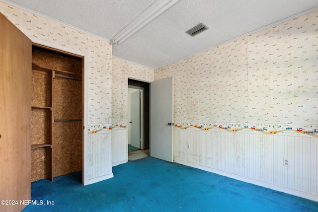 unfurnished bedroom featuring dark carpet, a textured ceiling, and ornamental molding