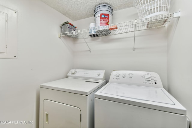 clothes washing area with electric panel, a textured ceiling, and independent washer and dryer