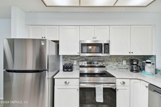 kitchen featuring white cabinets, appliances with stainless steel finishes, and tasteful backsplash