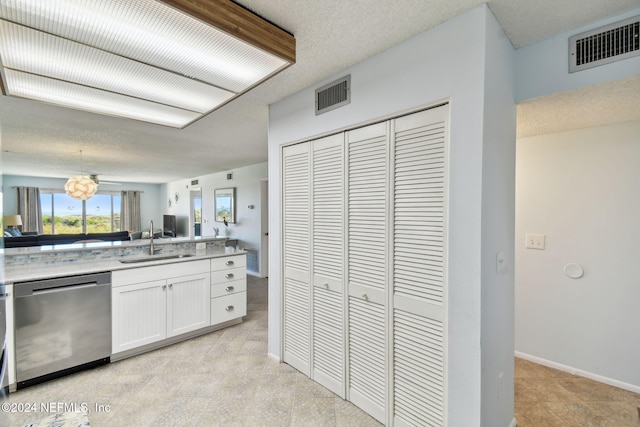 kitchen with dishwasher, light stone countertops, white cabinetry, and sink