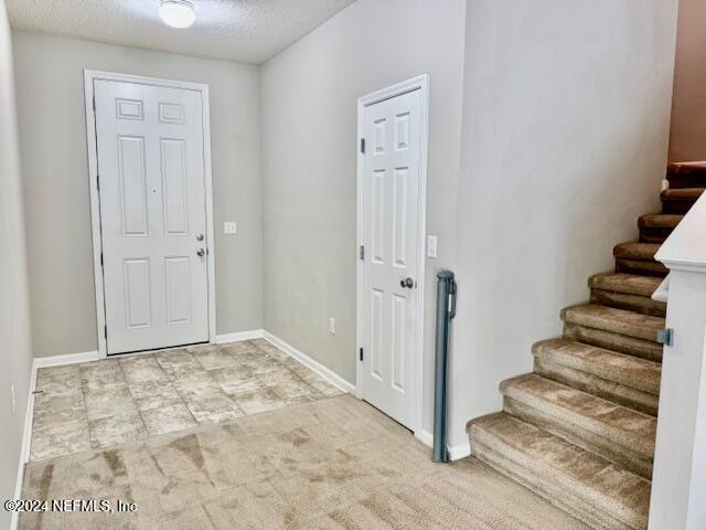 foyer entrance with light carpet and a textured ceiling