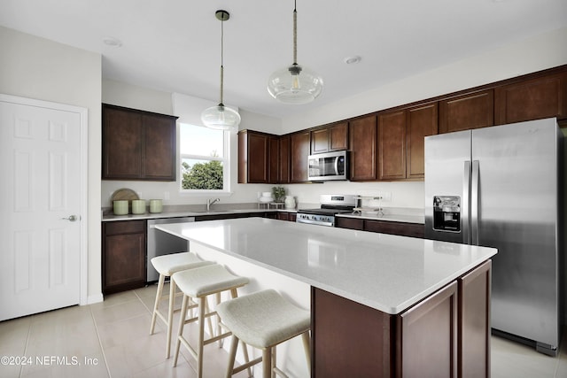 kitchen with sink, stainless steel appliances, decorative light fixtures, dark brown cabinets, and a kitchen island