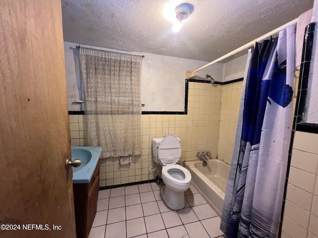 full bathroom featuring tile patterned floors, vanity, shower / bathtub combination with curtain, tile walls, and toilet