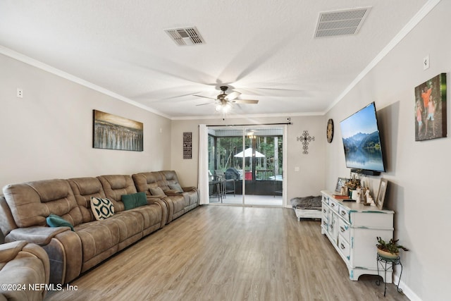 living room featuring a textured ceiling, ceiling fan, light wood-type flooring, and crown molding