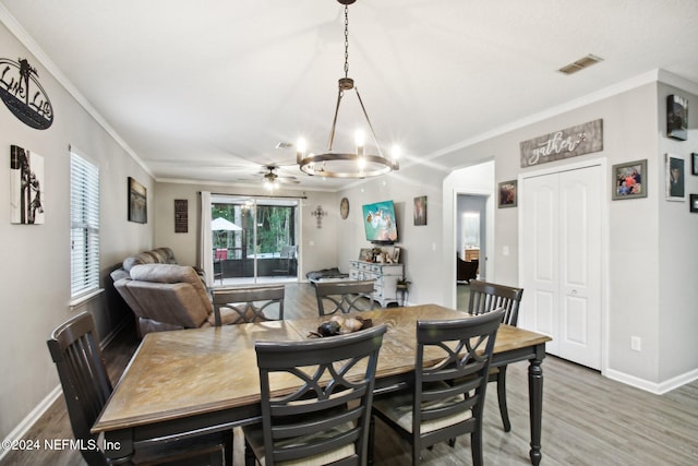 dining area with hardwood / wood-style flooring, ceiling fan with notable chandelier, and crown molding