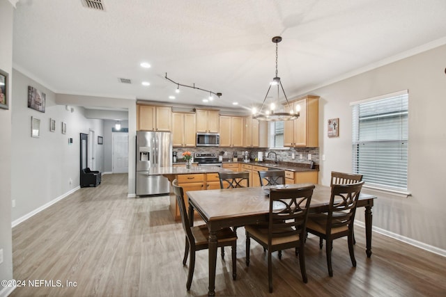 dining room featuring sink, light hardwood / wood-style flooring, a notable chandelier, crown molding, and a textured ceiling