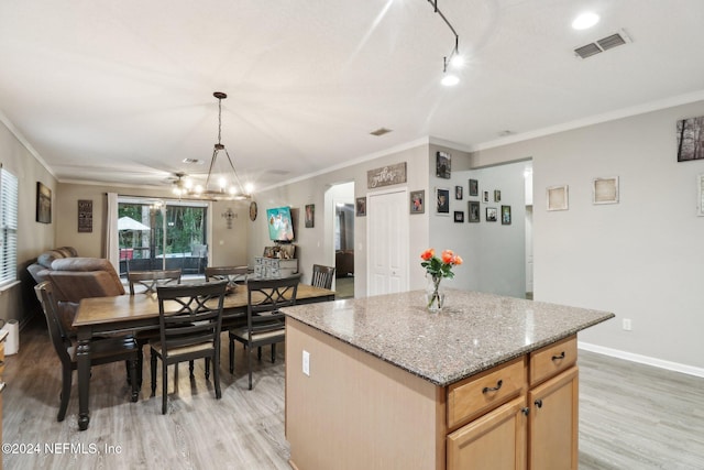 kitchen with crown molding, light hardwood / wood-style flooring, a kitchen island, and hanging light fixtures