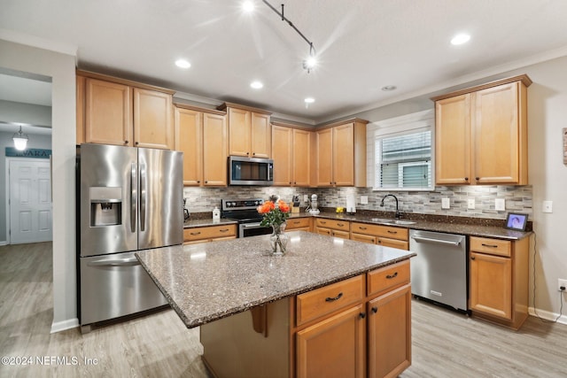 kitchen with light wood-type flooring, tasteful backsplash, ornamental molding, stainless steel appliances, and a kitchen island